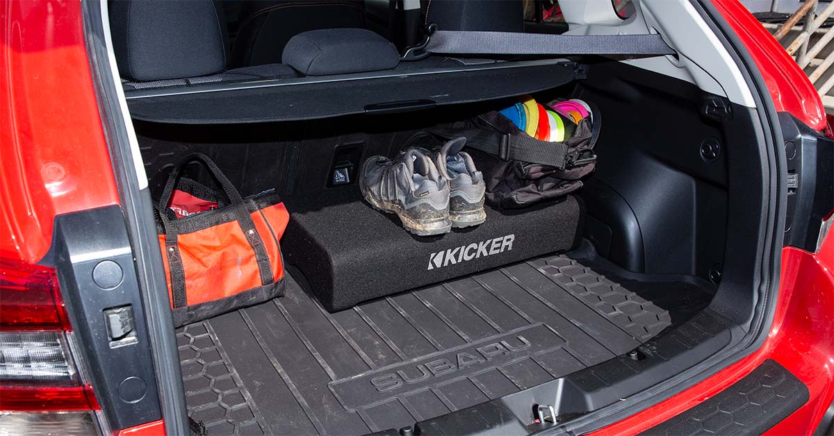 4-channel amplifier powering subwoofer setup in car cargo area
