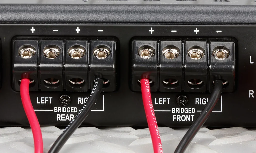 Close-up view of car amplifier installation and wiring for bridged stereo configuration