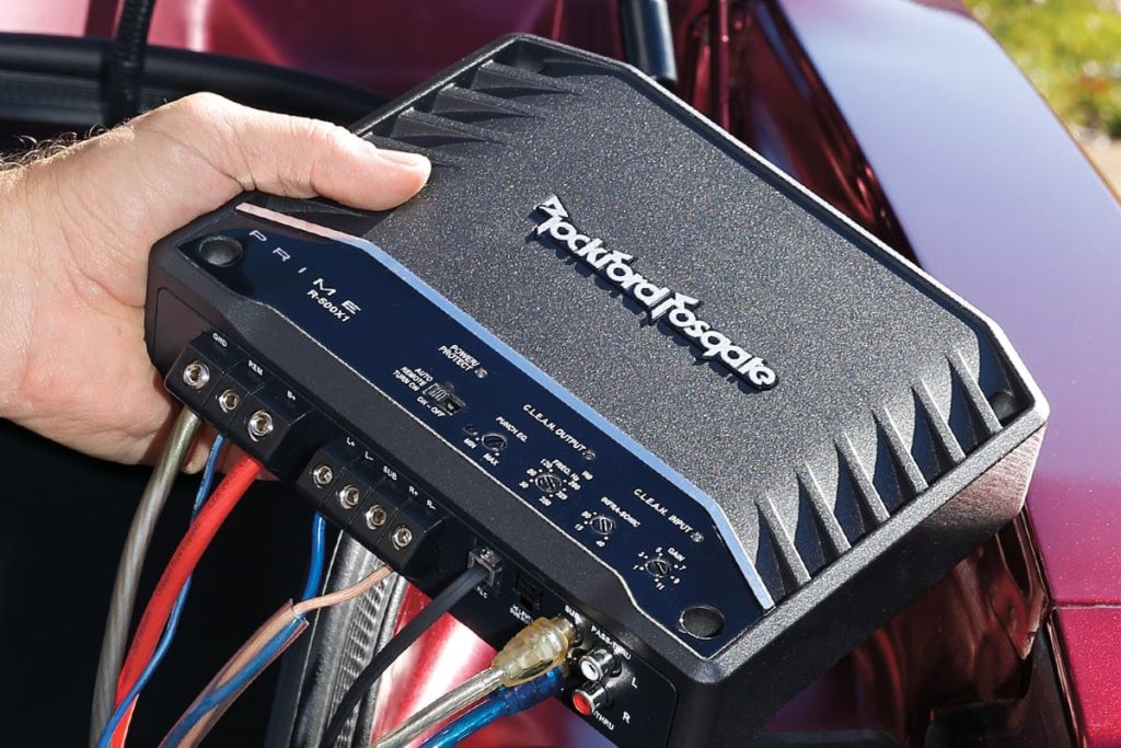 High-power car amplifier installed in trunk setup for deep bass performance.