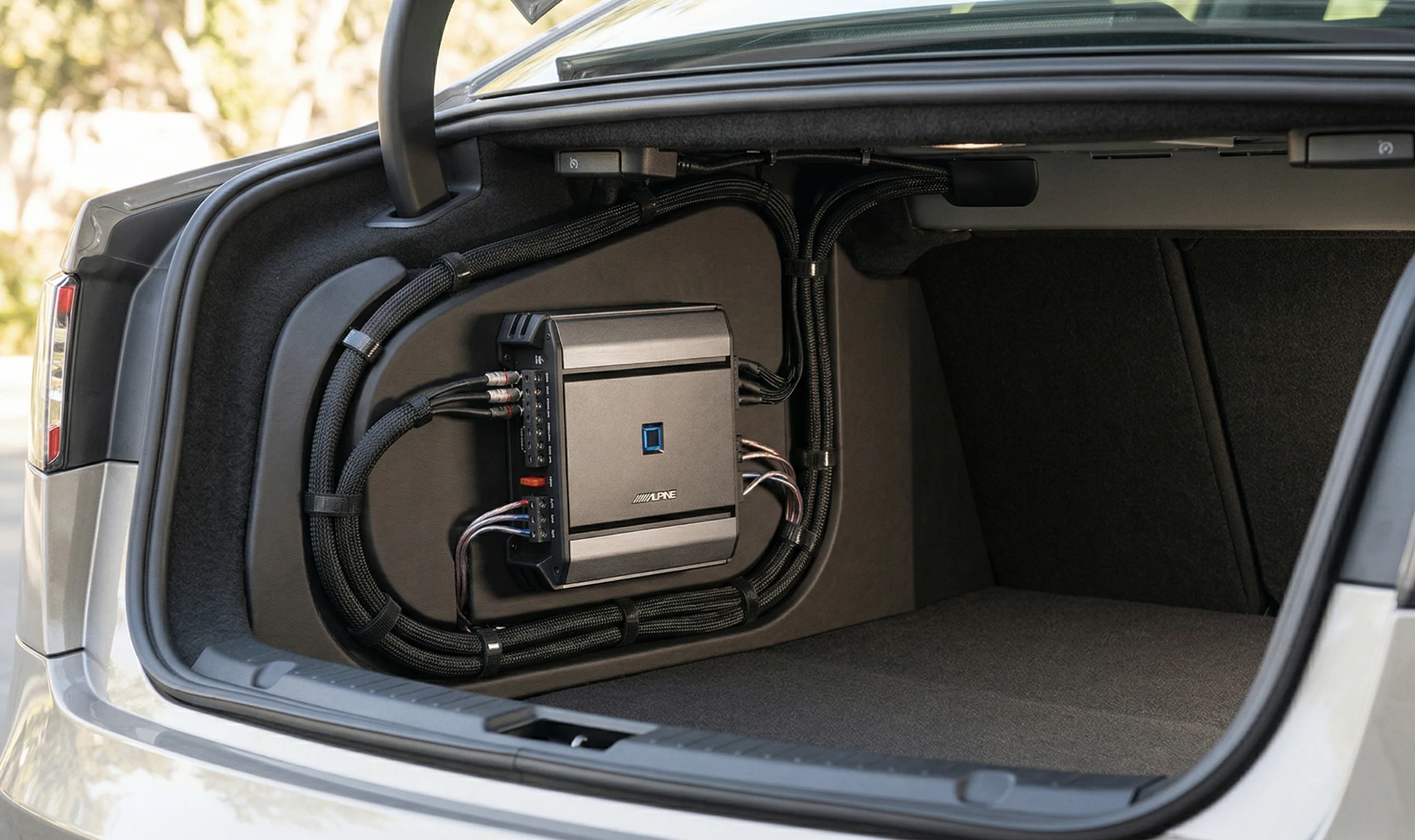 Alpine S-A32F amplifier mounted in car trunk with clean cable management and professional installation