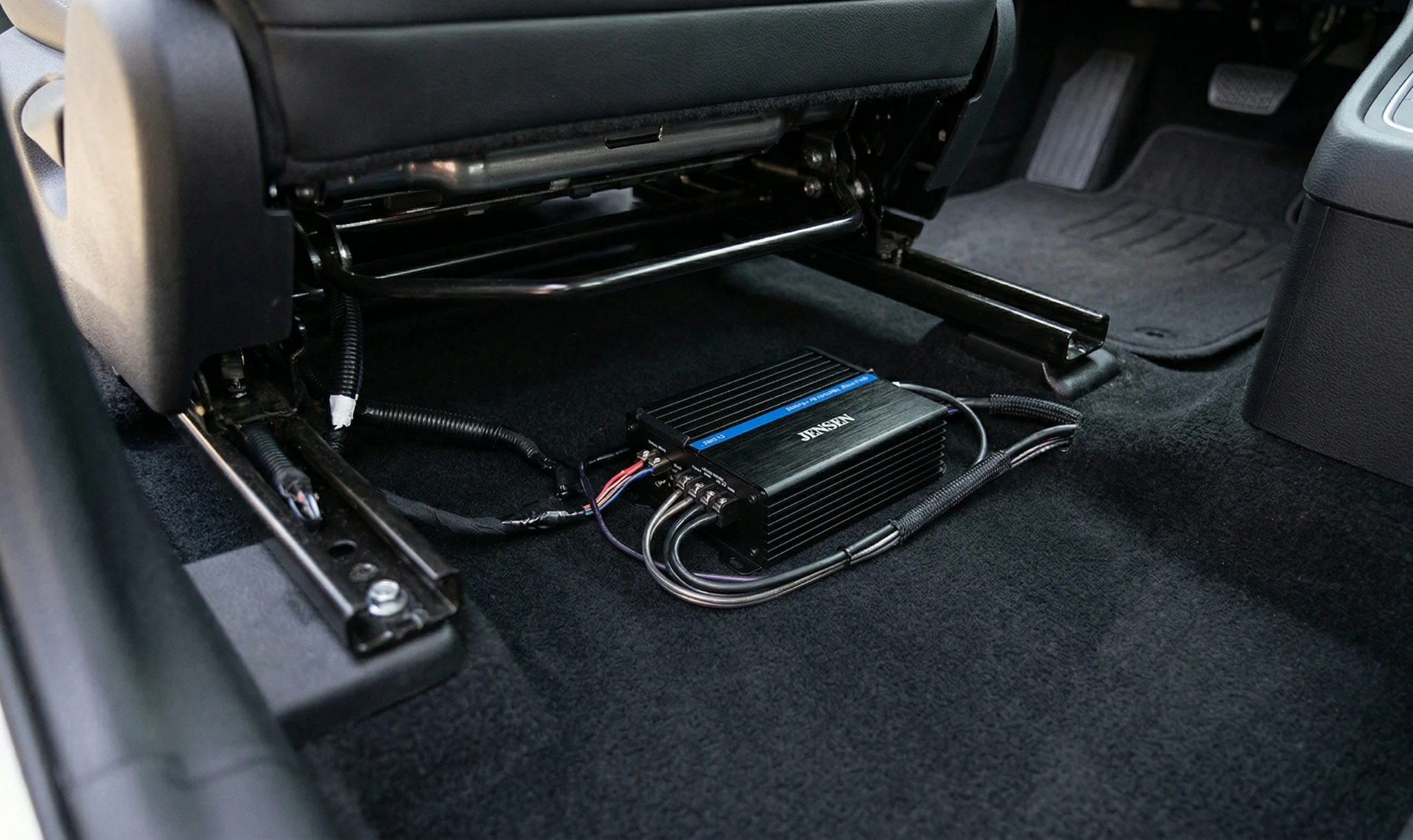Jensen compact 4-channel Class D amplifier installed under car seat with minimal wiring