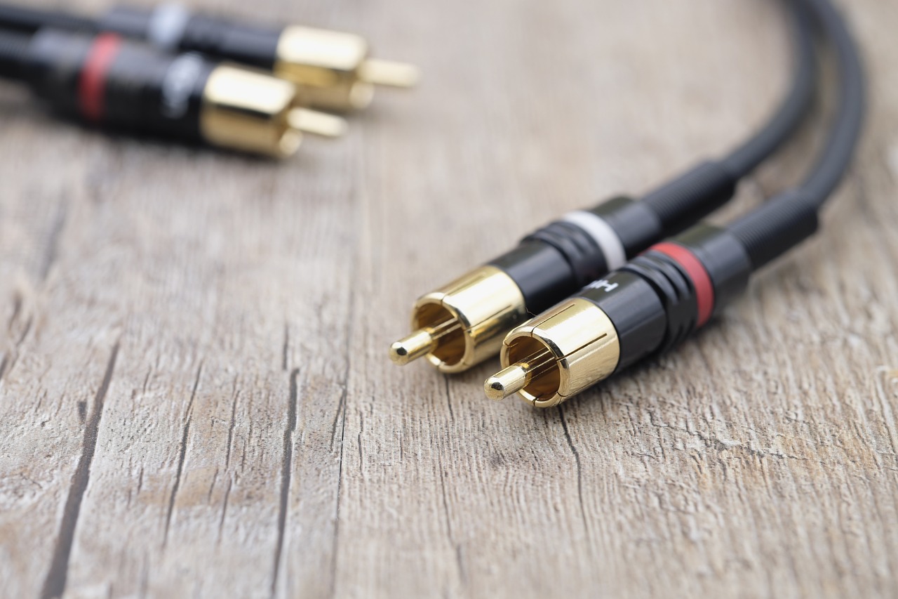 Gold-plated RCA audio cables on a wooden surface, used for analog connections