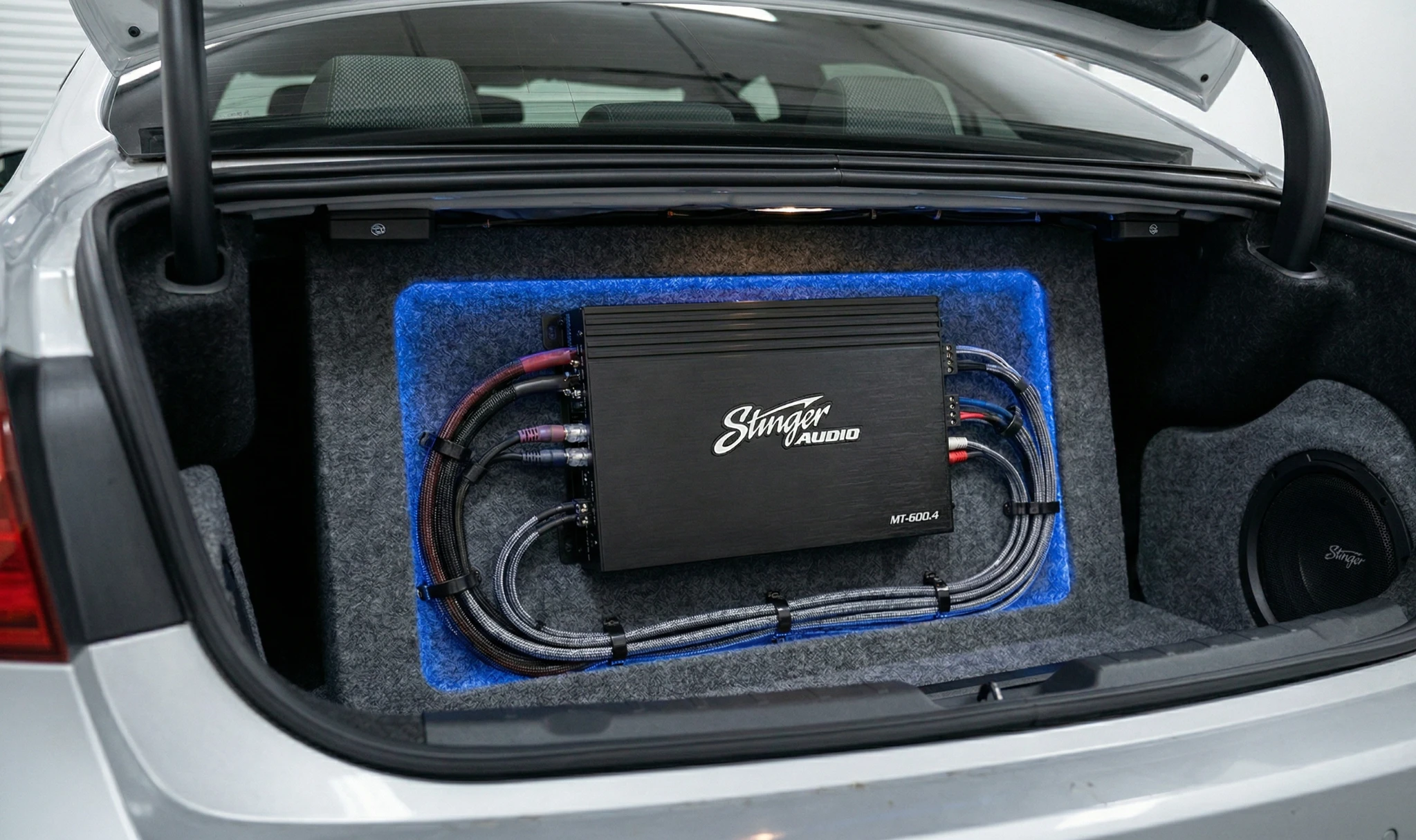 Stinger MT-600.4 4-channel car amplifier installed in trunk with clean cable routing