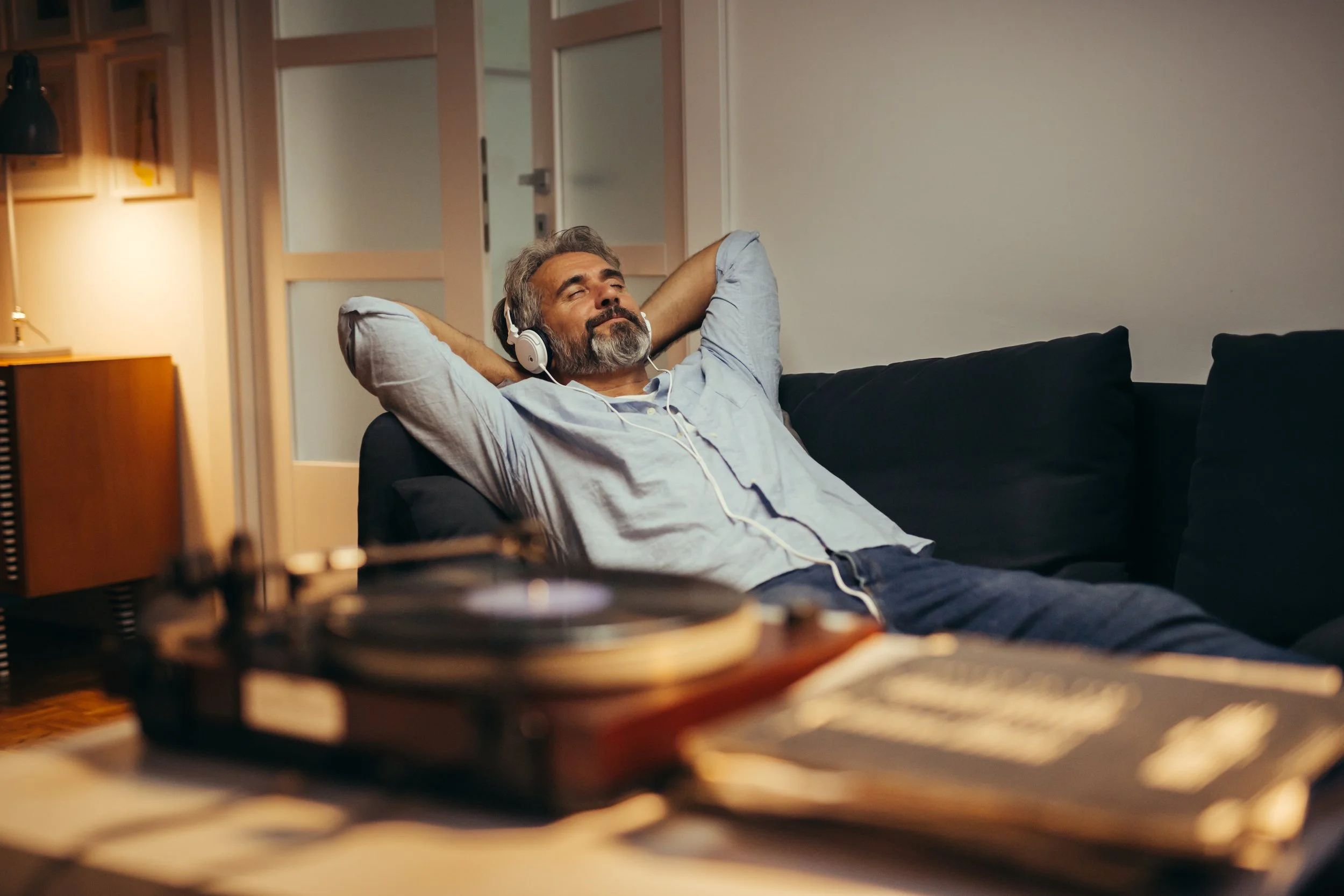 Listener relaxing on a sofa while reconsidering his audio setup and listening habits after choosing between a stereo amplifier and an AV receiver