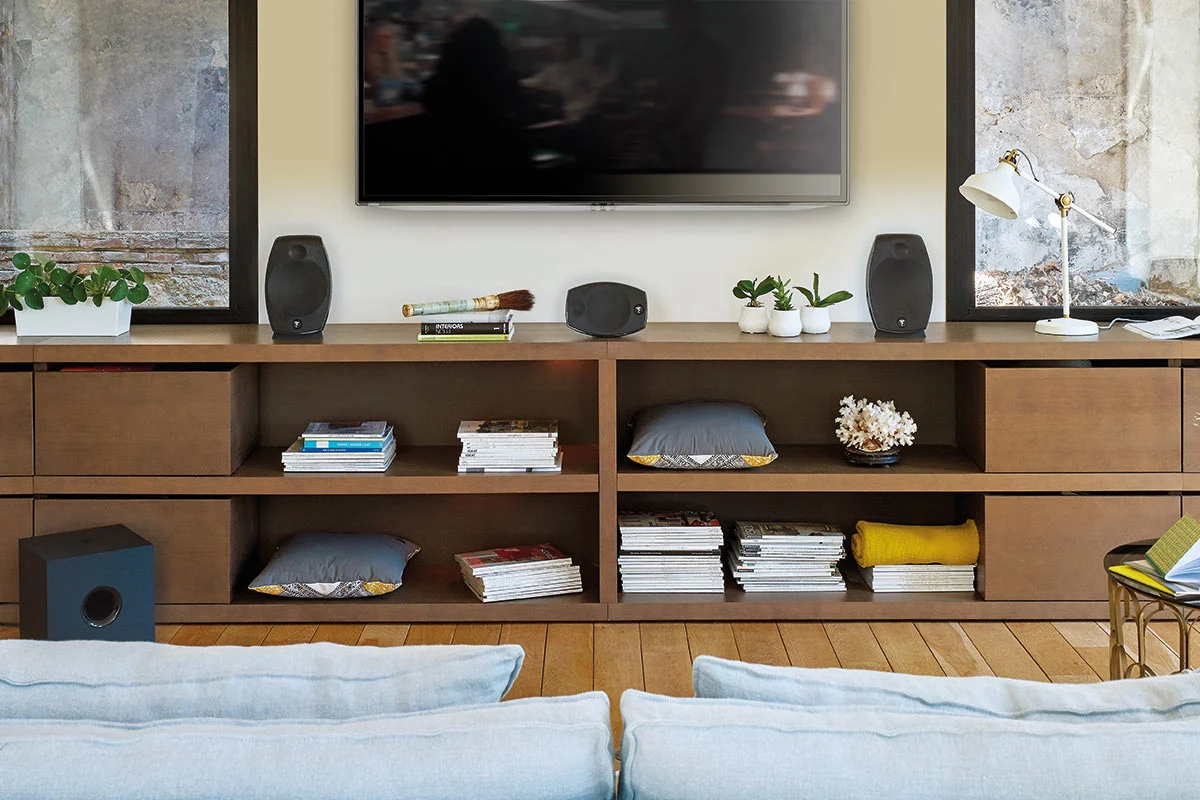 Minimal living room audio setup with two speakers, center channel, and subwoofer showing how speaker placement affects sound distribution