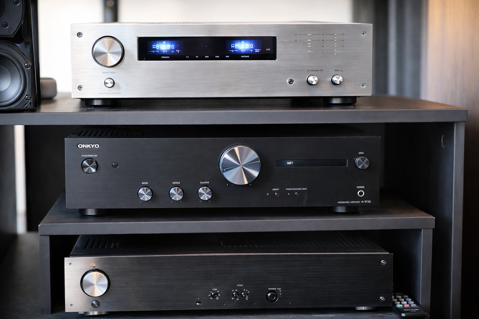 Stacked AV receiver, integrated amplifier, and power amplifier shown in a home audio rack