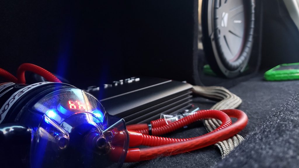 Car amplifier installation in vehicle trunk showing wiring and mounting setup